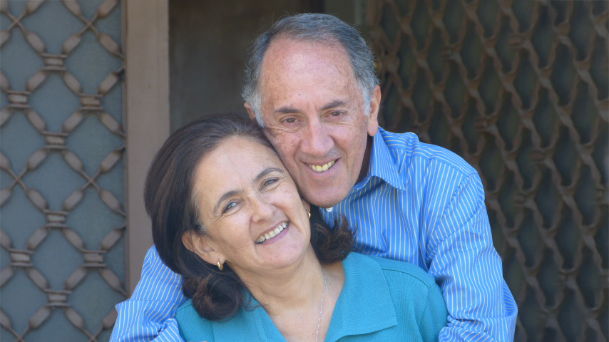 Claudio hugging his wife, both smiling brightly into the camera.