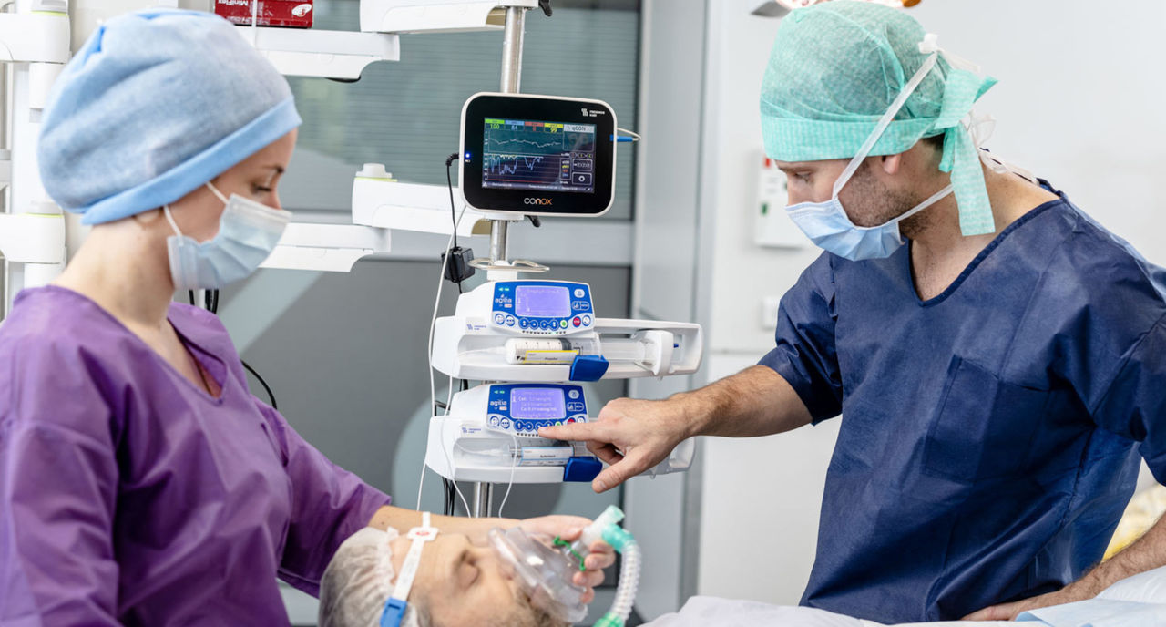Healthcare professionals monitoring medical equipment during a patient procedure.